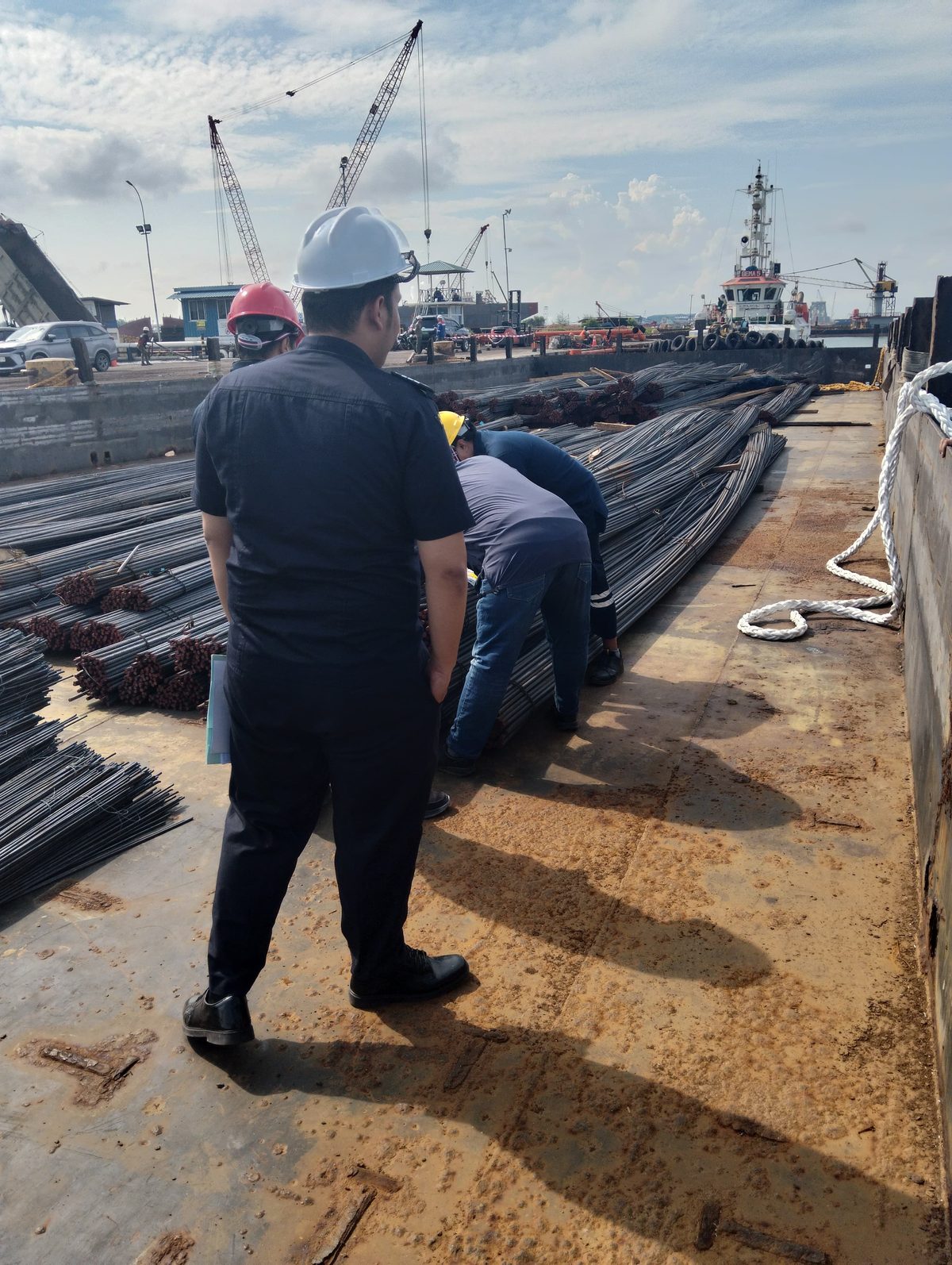 Kru berdiri memeriksa muatan besi beton di dermaga