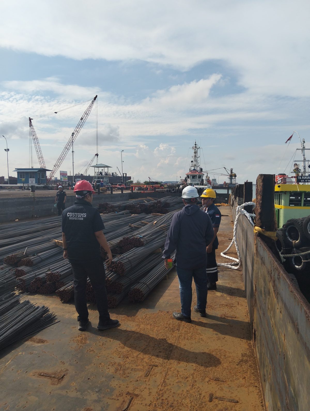 Tim berdiri di atas tongkang bermuatan besi beton